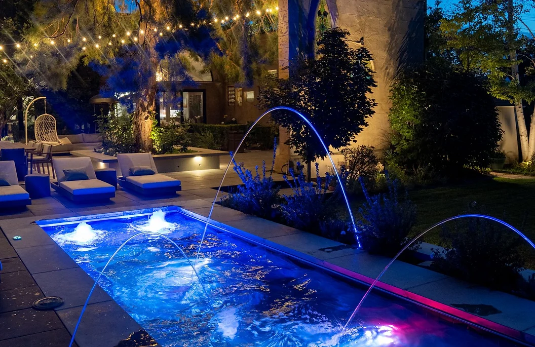 outdoor swimming pool with water feature lit up at night - precision pools