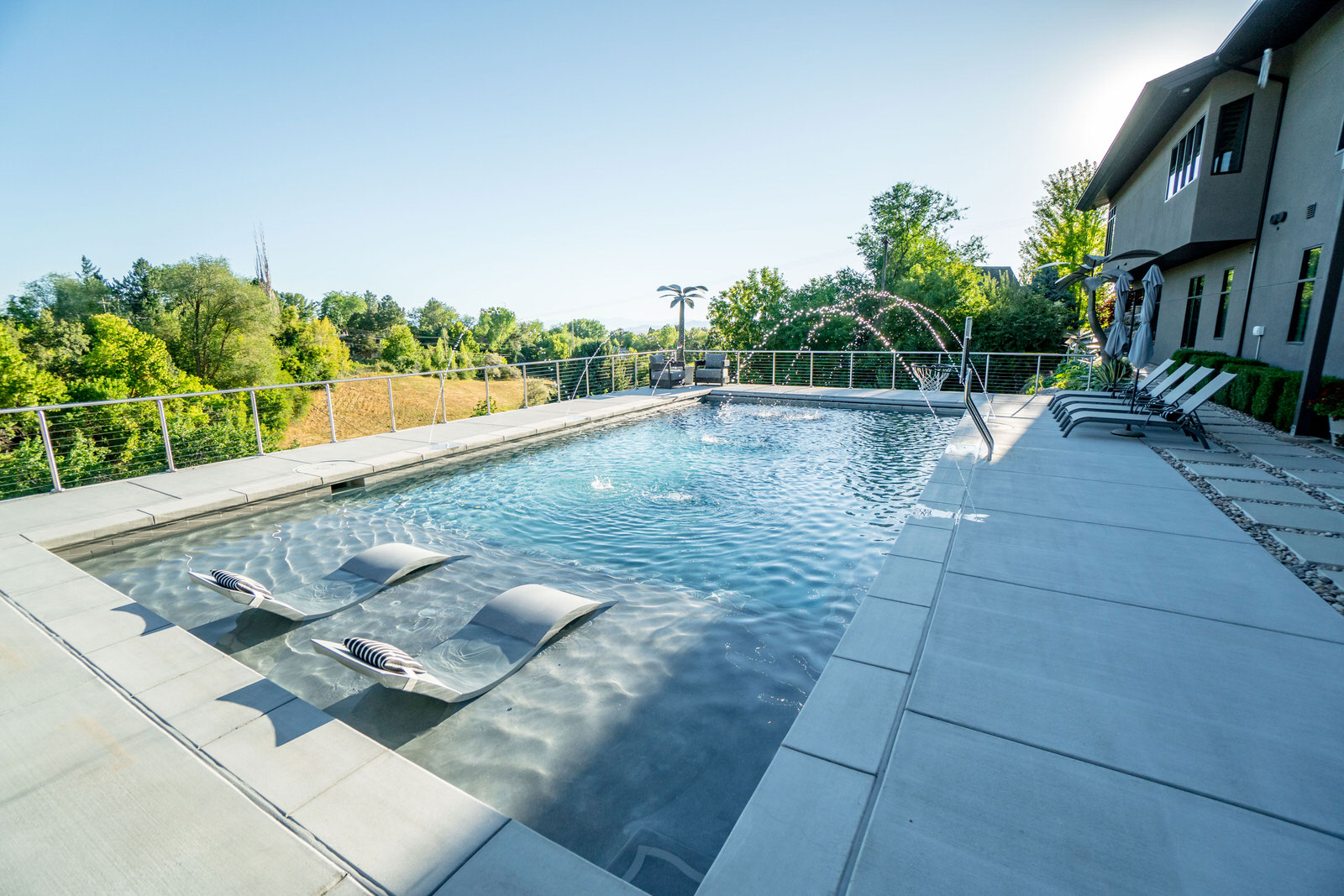 Swimming pool with jet fountains and sun beds in the pool - Precision Pools