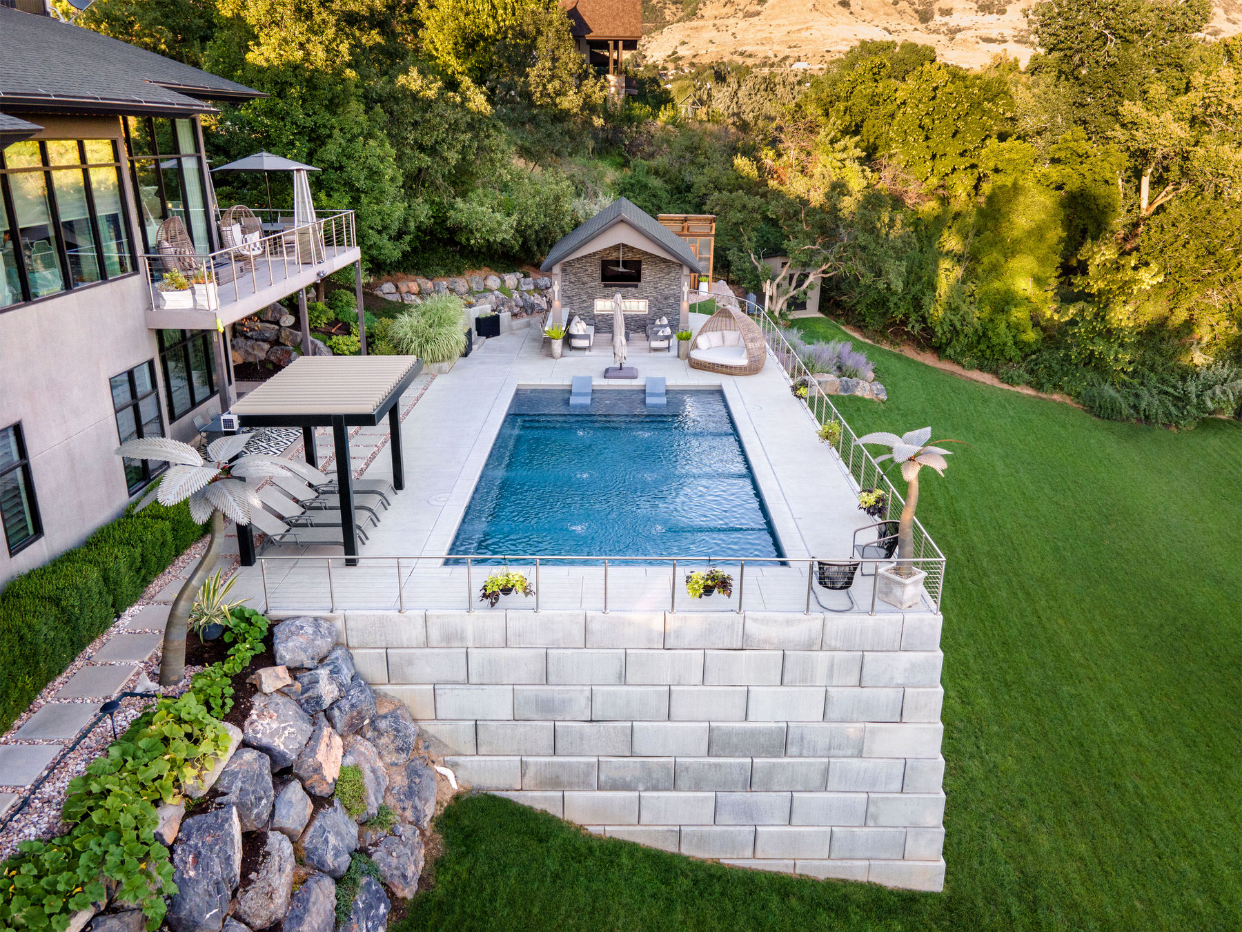 Luxury private swimming pool overlooking green garden with outbuilding and sun beds - Precision Pools