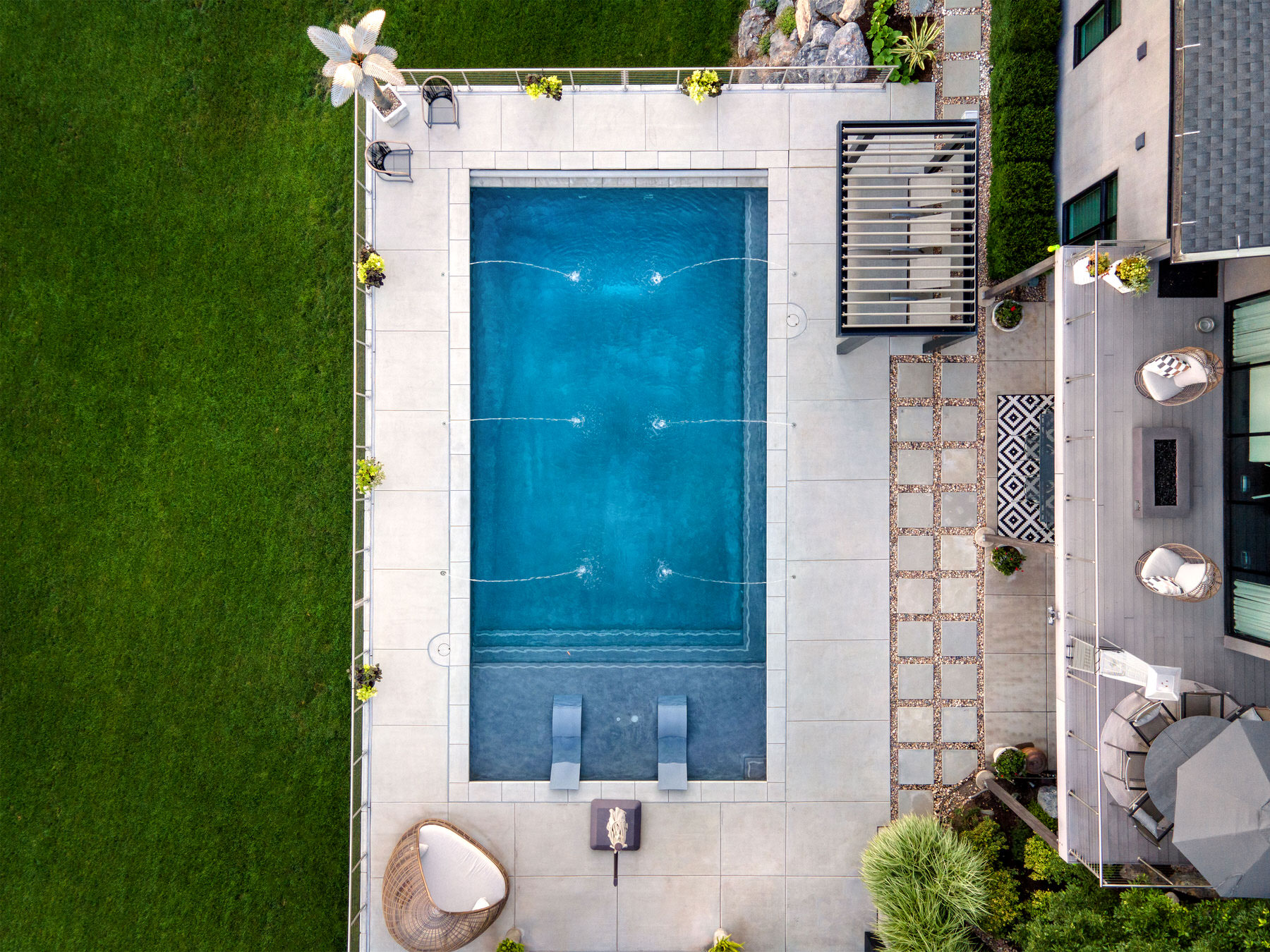 private swimming pool with jet fountains and sun beds in the pool - Precision Pools